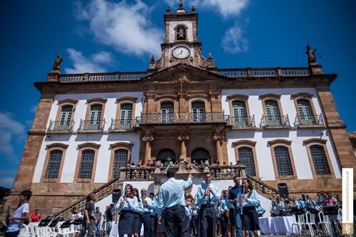   23/11/2018  Vale investe R$ 14,7 bilhões em Minas Gerais nos primeiros nove meses de 2018. Área do Complexo Mariana e Brucutu recebeu ações com estes recursos.  Os principais tributos pagos somaram R$ 1,1 bilhão no período. Somente a CFEM foi de R$ 502,3 milhões para 14 municípios produtores. Os desembolsos da Vale em Minas Gerais nos primeiros nove meses do ano ultrapassaram R$ 14,7 bilhões entre custeio e investimentos nas áreas de Mineração, Logística e Pesquisa Mineral, entre outros.  As atividades da Vale geraram arrecadação de R$ 1,1 bilhão entre janeiro e setembro de 2018 em Minas, considerando-se os tributos mais importantes. Os valores são repassados pela Vale à Agência Nacional de Mineração (ANM), que faz a distribuição para os municípios mineradores, Estado, União e outras entidades.  Estão incluídos no montante a Compensação Financeira pela Exploração de Recursos Minerais (CFEM), o Imposto sobre Circulação de Mercadorias e Serviços (ICMS), a Taxa de Controle, Monitoramento e Fiscalização das Atividades de Exploração e Aproveitamento de Recursos Minerários (TFRM) e o Imposto Sobre Serviços de Qualquer Natureza (ISS). Apenas o repasse da CFEM (Compensação Financeira pela Exploração de Recursos Minerais) para 14 municípios produtores foi equivalente a R$ 502,3 milhões nesse período.    São Gonçalo do Rio Abaixo, onde está localizada a Mina de Brucutu, é um dos municípios que recebem CFEM devido às operações da Vale.  Para suportar suas operações, a Vale conta com quase 26 mil empregados próprios e terceiros permanentes no Estado.     Atuação sustentável  Investimento social  A Vale investiu, nos primeiros nove meses, R$ 184,3 milhões em ações e projetos socioambientais. Apenas a Fundação Vale, braço social da empresa, destinou R$ 5,9 milhões para inciativas sociais de Minas Gerais. Os projetos Apoio à Geração e Incremento de Renda (AGIR), Programa de Empreendedorismo Social Comunitário (PESC) e Equidade de Gênero são exemplos do trabalho desenvolvido pela Fundação para prospectar, promover e incubar negócios sociais.  Ações de fortalecimento da Atenção Básica e da educação nas comunidades onde a empresa atua também receberam investimentos. O Projeto Saberes, parceria entre Vale, SESI Mariana e Prefeitura Municipal, promoveu o compartilhamento de conhecimento e incentivo à leitura, arte e cultura por meio de um caminhão biblioteca que beneficiou 4.343 pessoas em Mariana, Ouro Preto e Catas Altas. No campo da Educação Inclusiva, nos municípios de Barão de Cocais, São Gonçalo do Rio Abaixo e Santa Bárbara está sendo feita a sistematização das experiências recentes que envolvem formação de profissionais e montagem de salas de recursos multifuncionais.  A Vale também mantém o único trem diário que liga duas capitais do país, Belo Horizonte e a Grande Vitória, passando por 42 municípios, e o Trem Turístico que conecta as cidades históricas de Ouro Preto e Mariana. De janeiro a setembro de 2018, a Estrada de Ferro Vitória a Minas (EFVM) transportou mais de 826 mil passageiros e o Trem Turístico já recebeu mais de 65 mil pessoas.  Edição do Trem da Vale Jazz reuniu 450 pessoas em setembro no passeio noturno entre Mariana e Ouro Preto  Já os investimentos da Vale em patrocínio no Estado serão da ordem de R$ 14 milhões até o final de 2018, seja via Lei Rouanet ou recurso direto. O Memorial Minas Gerais Vale, mantido pela empresa, conta com recursos no valor de R$ 4 milhões neste ano e já recebeu mais de 90 mil visitantes em 2018. A Vale também renovou sua parceria com Inhotim, museu que apoia desde 2011, sendo responsável pelo patrocínio que garante a manutenção do Instituto e dos projetos Jovens Agentes e Escola de Cordas.  Neste ano, a Vale apoiou ainda os Festivais de Ouro Preto e Mariana com a realização de ações no Trem Turístico e apresentações da Orquestra Ouro Preto.  Além disso, mais de 120 músicos participaram do encontro de bandas promovido pela Orquestra Ouro Preto no início de setembro. Esta ação beneficiou mais de 500 pessoas por meio dos cursos promovidos pelo Núcleo de Apoio a Bandas e Corporações Musicais. O projeto conta com o patrocínio da Vale por meio da Lei de Incentivo à Cultura.  Compromisso com as tradições - mais de 120 músicos participaram do encontro de bandas promovido pela Orquestra Ouro Preto